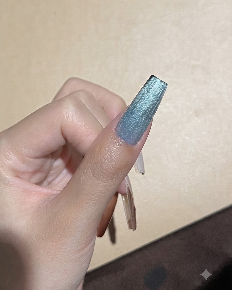 Silny magnes trzymany blisko niebieskiego paznokcia z żelem cat-eye w celu dopracowania linii odbicia światła.