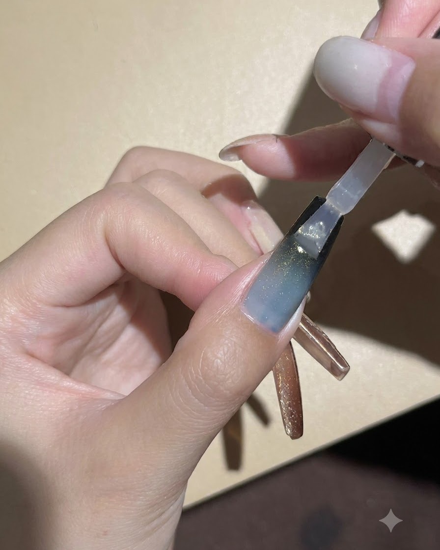 Pędzelek do paznokci nakładający przezroczysty, błyszczący top coat na ciemny gradient i żel cat-eye.