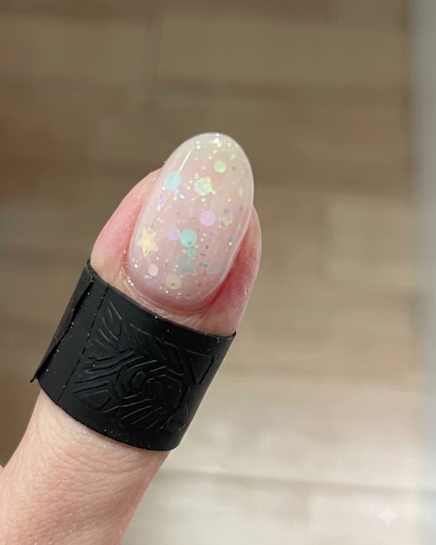 Eine Nahaufnahme eines Fingernagels mit einem leuchtenden Cat-Eye-Gel-Effekt, bei dem sich helle Schimmereffekte an der Nagelspitze über Stern-Glitzern konzentrieren.