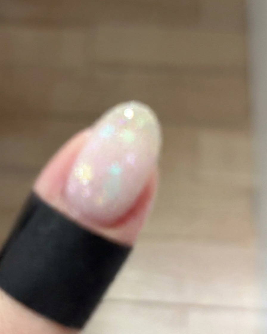 Ein kleiner Make-up-Schwamm tupft sanft staubrosafarbenes Gel auf die Mitte eines manikürten Nagels, um einen weichen Blush-Gradienten zu erzeugen.
