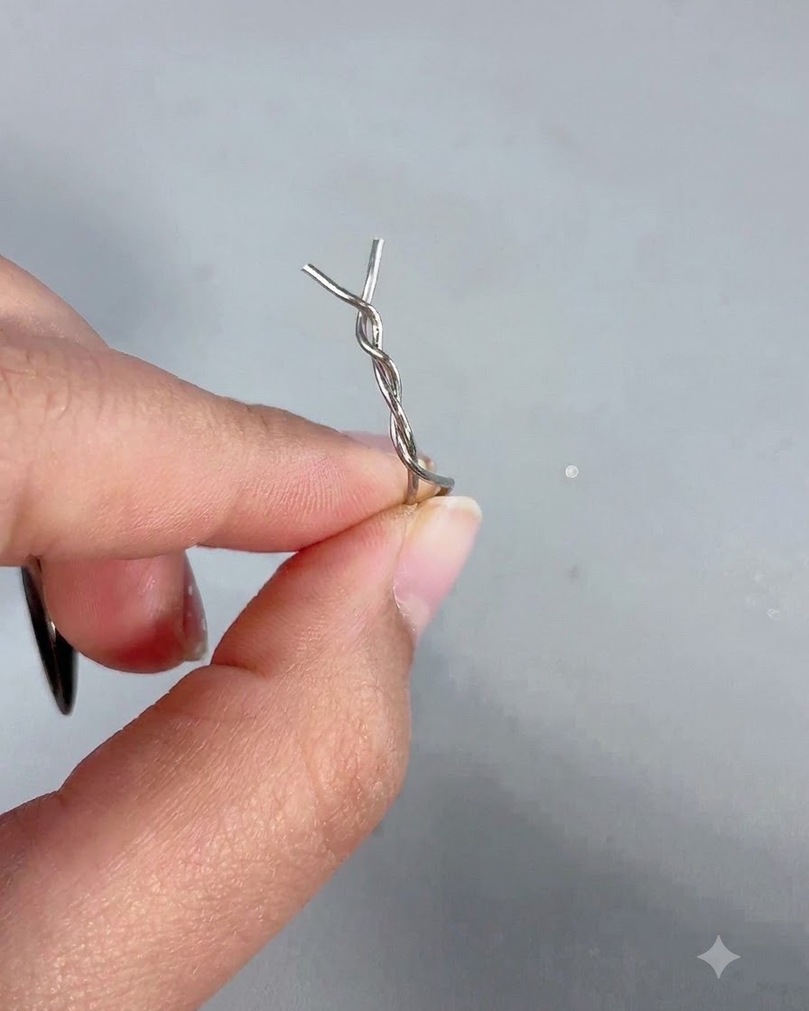 Dłoń trzymająca różdżkę magnetyczną z przymocowaną do jej końcówki skręconą metalową wsuwką do włosów.