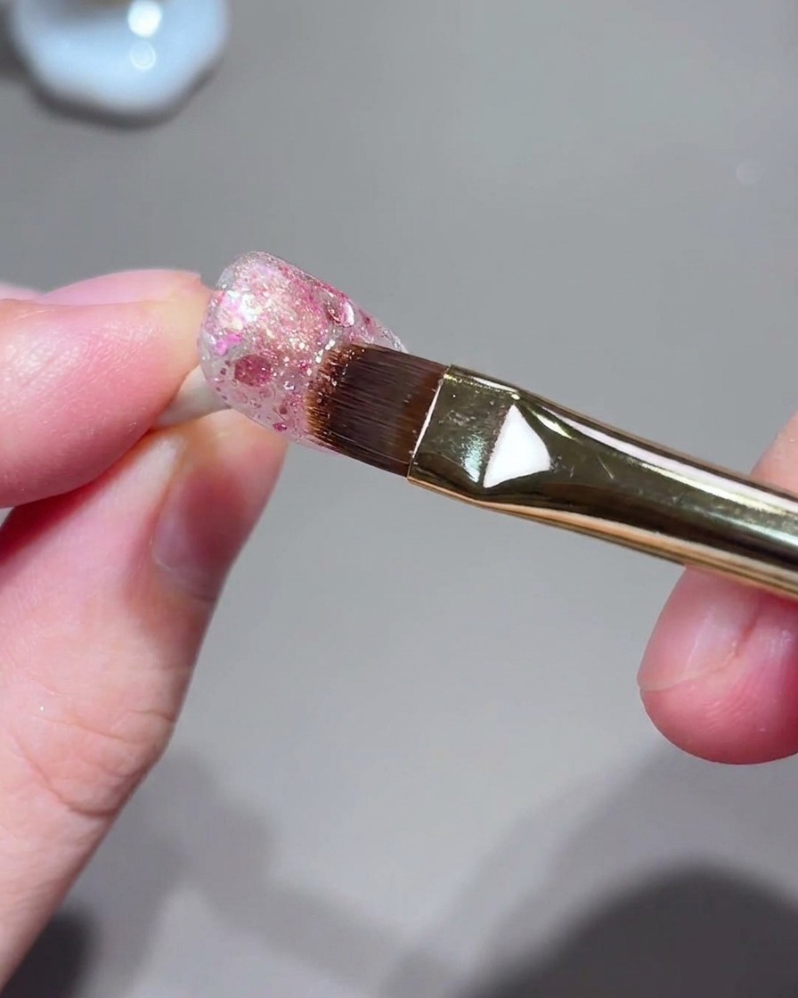Pędzelek i zestaw paznokci podczas procesu magnetycznego przyciągania światła cat-eye.
