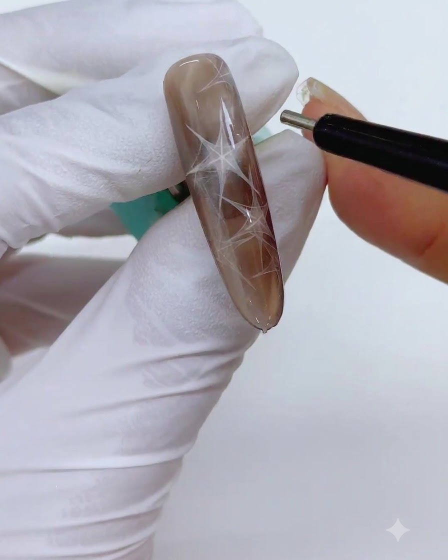 Precyzyjne magnetyczne narzędzie w kształcie długopisu trzymane blisko paznokcia w celu wyostrzenia krawędzi magnetycznego trójkąta.