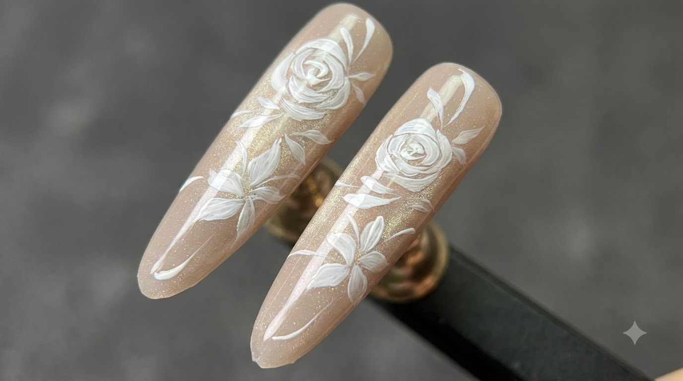 Dwa gotowe przedłużenia paznokci w kształcie migdałka z połyskującą bazą cat-eye w odcieniu nude, ozdobione delikatnymi, ręcznie malowanymi białymi różami i gałązkami z liśćmi.