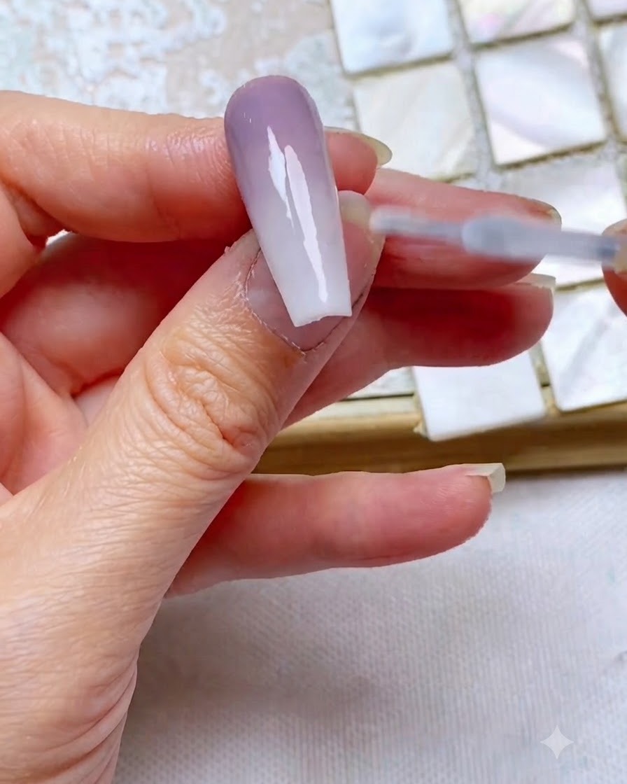 Pędzelek od topu gładko sunący po wykończonym, dwutonowym paznokciu z gradientem, aby go zabezpieczyć i nadać połysk.