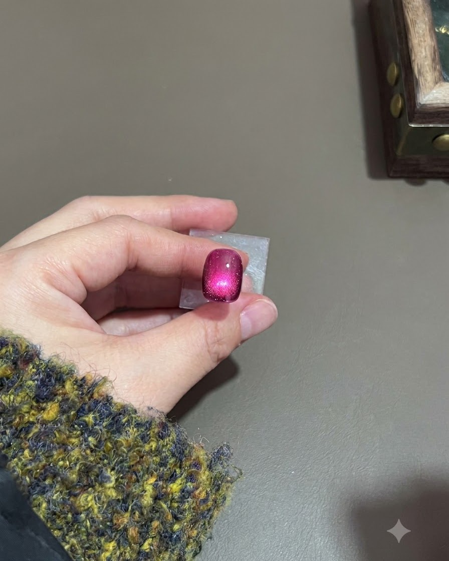 Ciemnofioletowy paznokieć cat-eye z utwardzonym, świecącym rozświetleniem pod lampą.