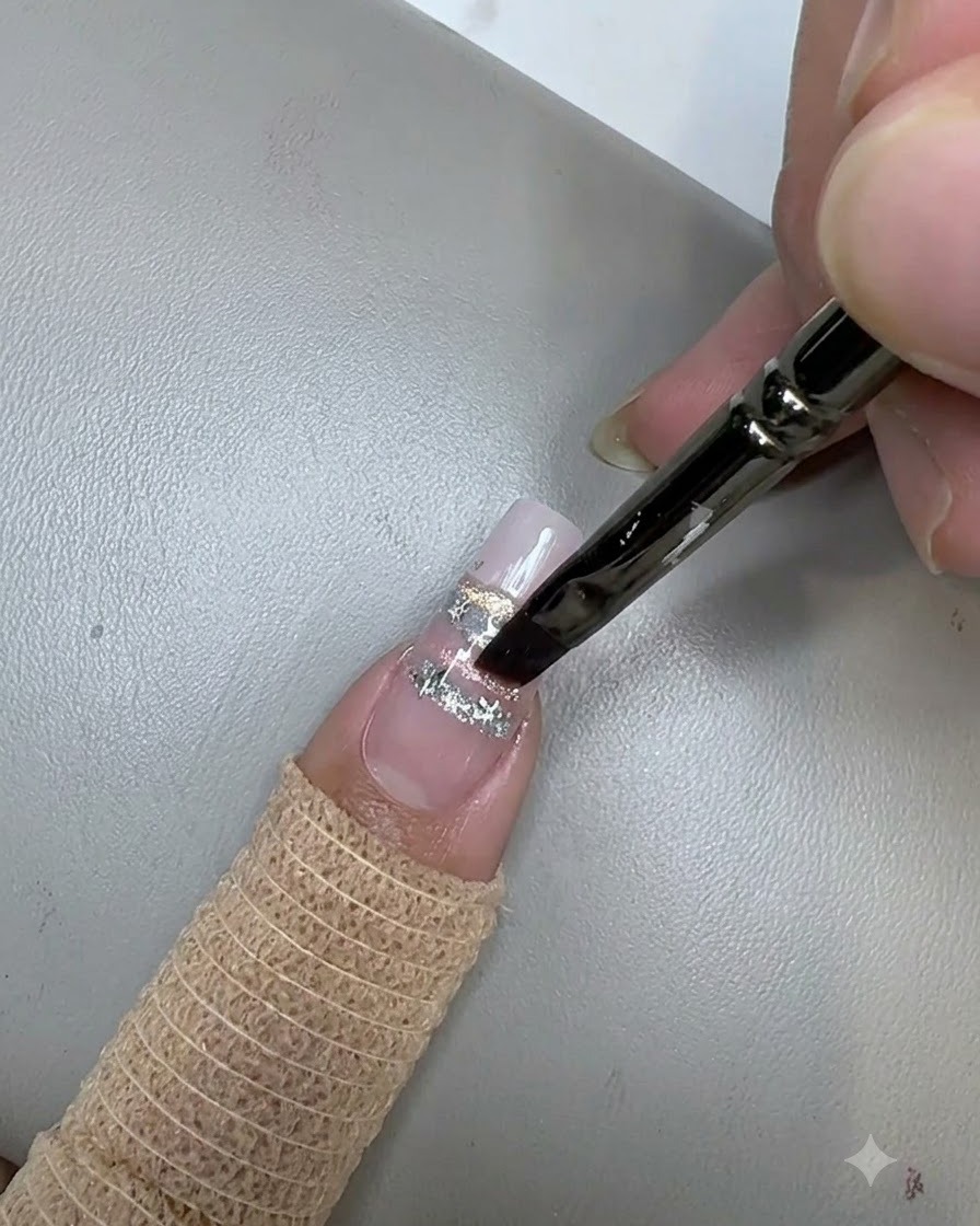 Pędzelek do paznokci aplikujący bezbarwny top coat na gwiazdki i ozdobiony paznokieć.