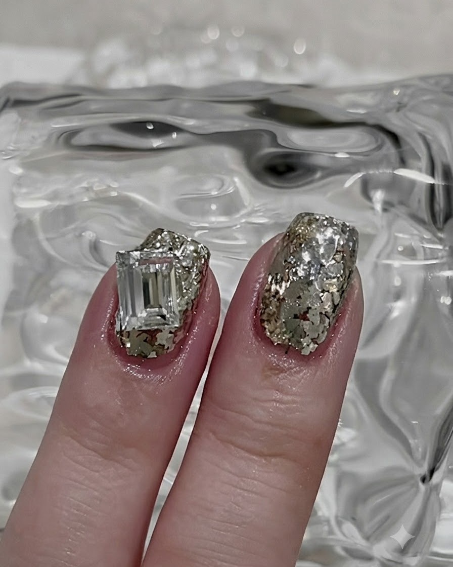 Cienki pędzelek do nail artu nabierający niewielką porcję sypkiego srebrnego brokatu.