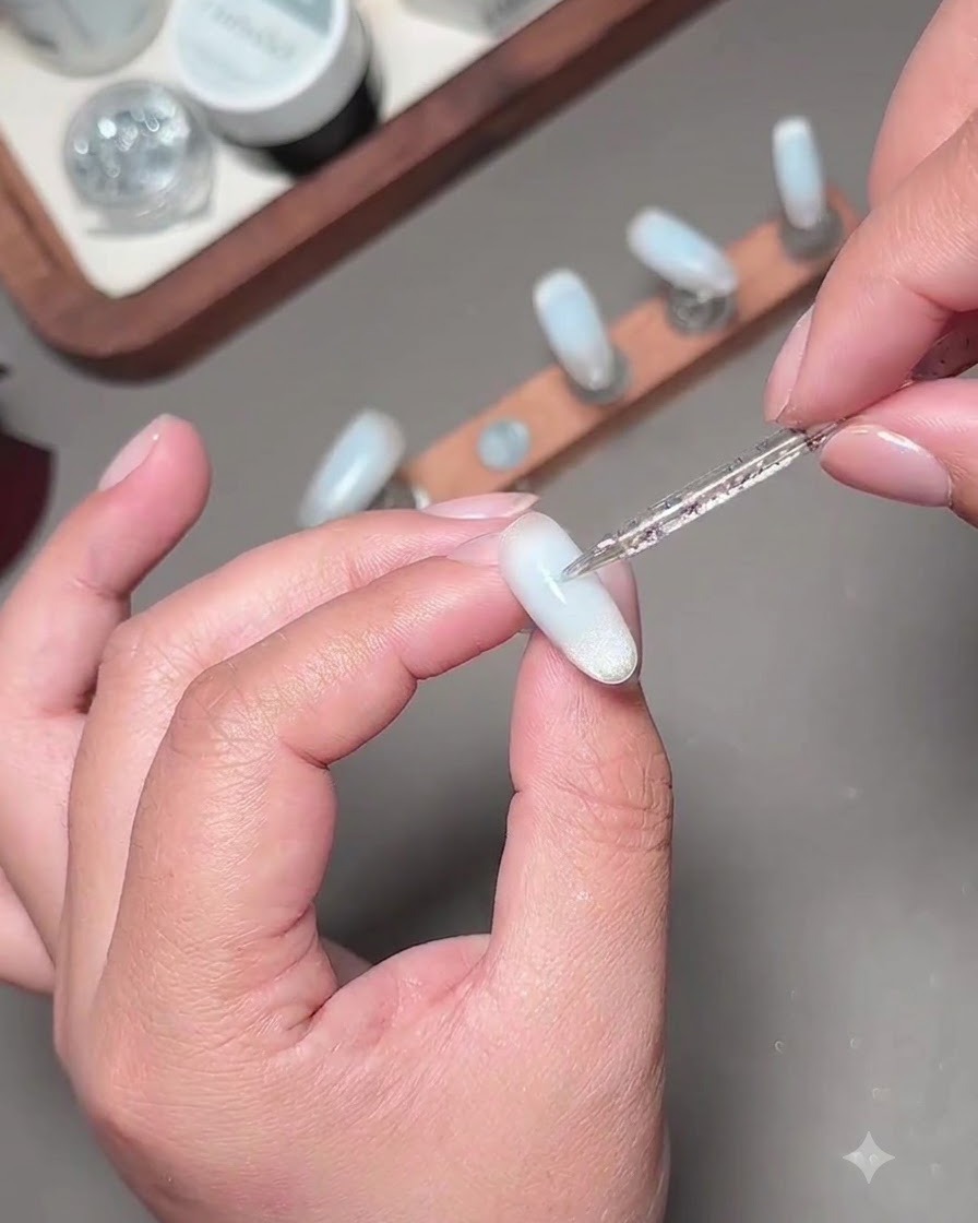 Cienki pędzelek do nail artu nakładający drugą warstwę niebieskiego żelu w celu przyciemnienia środka paznokcia.