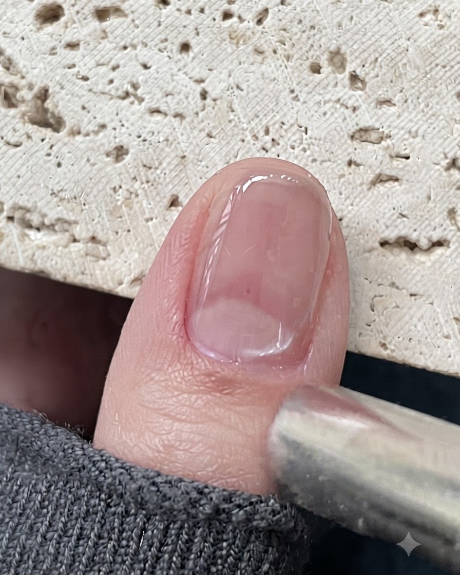 Narzędzie magnetyczne umieszczone blisko błyszczącego paznokcia z żelem cat eye, przyciągające cząsteczki magnetyczne.
