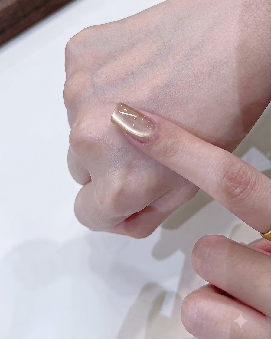Narzędzie magnetyczne kształtujące miękki refleks jednostronnego światła na szampańsko-złotym paznokciu cat eye.