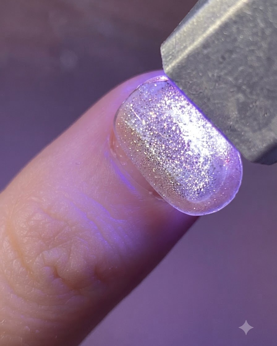 Metalowa pęseta podnosząca holograficzną naklejkę gwiazdkę z przezroczystego arkusza.