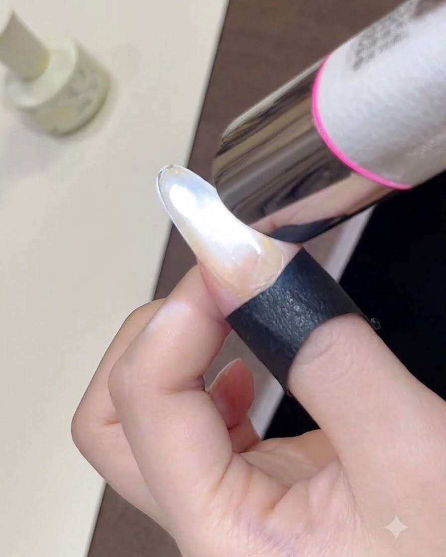 Zbliżenie na ręczną mini lampę UV utwardzającą świeżo wymodelowany, błyszczący lakier hybrydowy cat-eye na paznokciu.