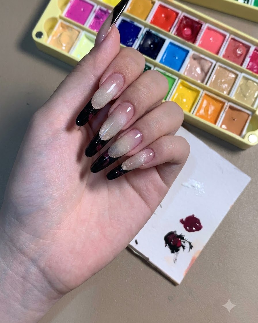 Dłoń prezentująca paznokcie szpice z czarnymi końcówkami french i konturami ciemnych śliwkowych róż.