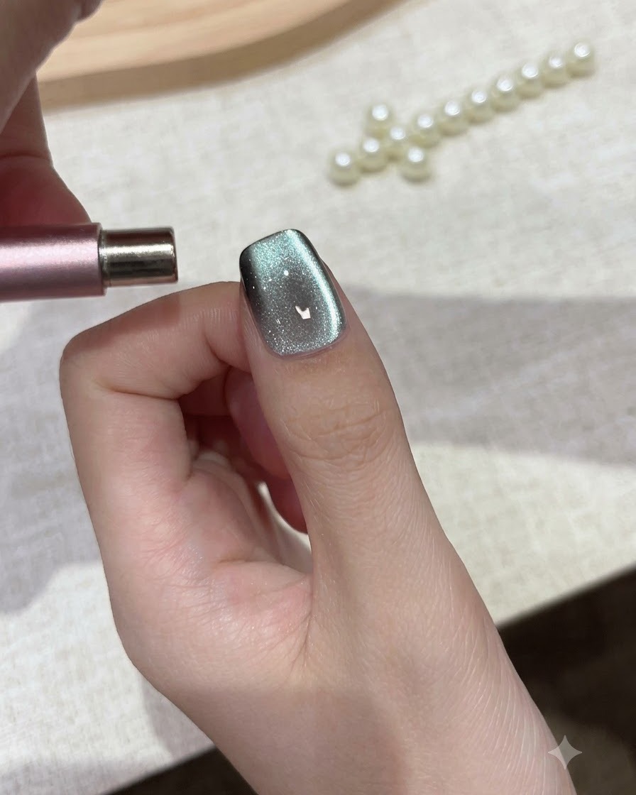 Ein zylindrischer Magnet wird parallel zur Nagelspitze gehalten, um Cat-Eye-Gelpartikel zu formen.
