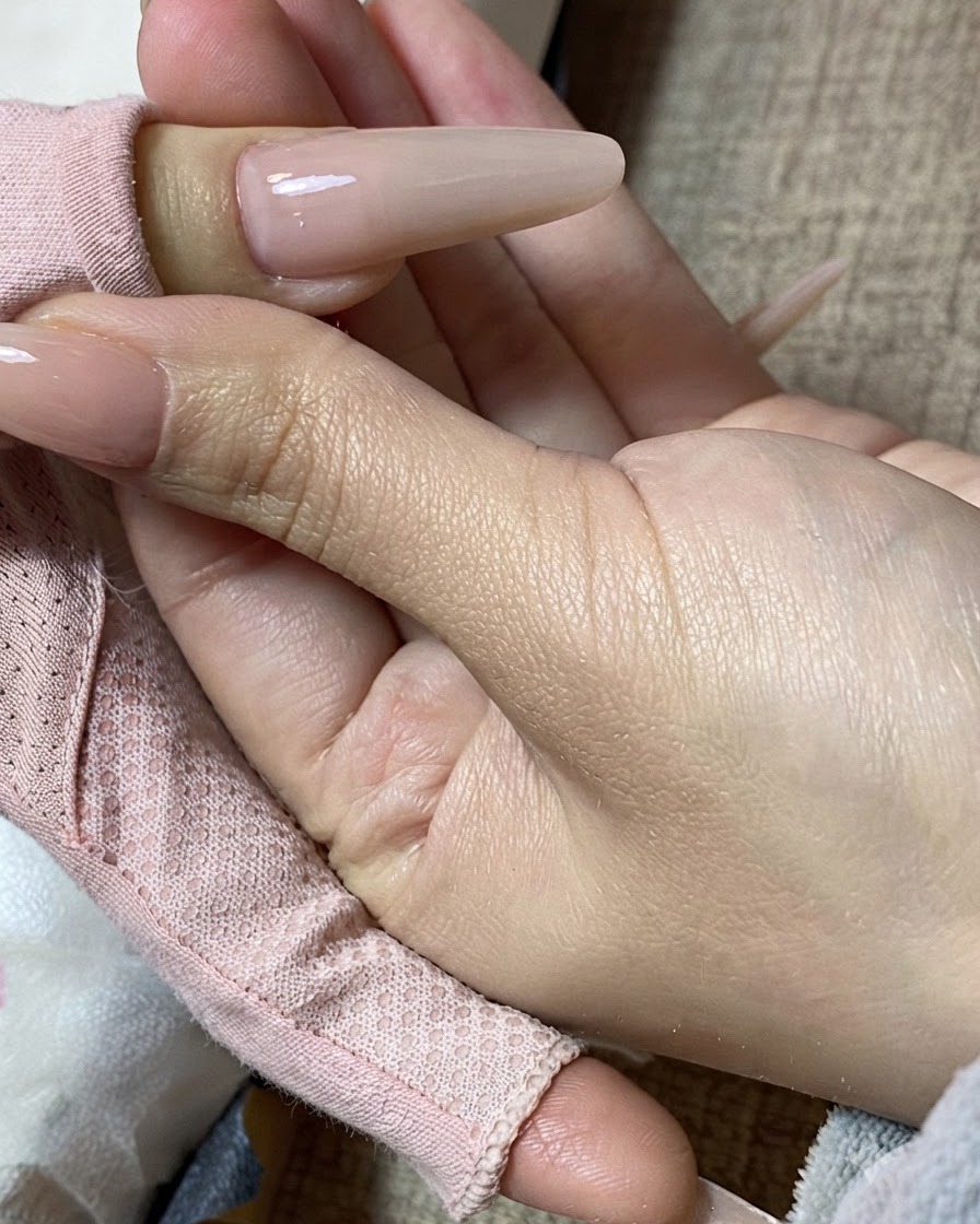 Zbliżenie dłoni trzymającej gotowy paznokieć z mlecznym manicure.