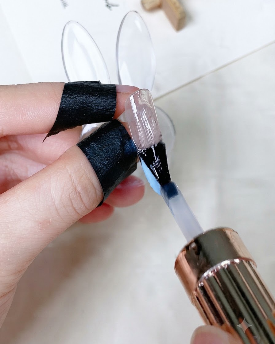 Pędzelek nakładający bezbarwny, błyszczący top coat na pomalowany paznokieć.
