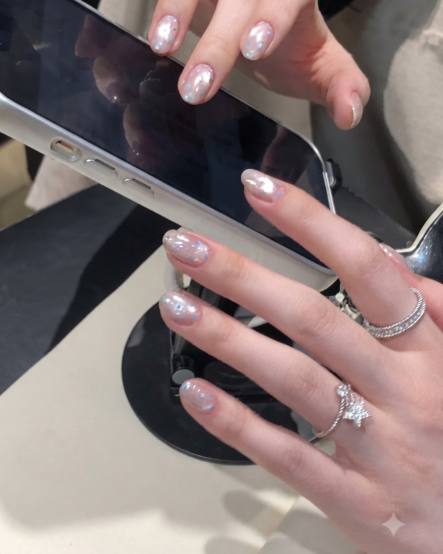 Pędzelek do paznokci nakładający przezroczysty top nawierzchniowy na krótkie paznokcie z efektem aurora chrome.