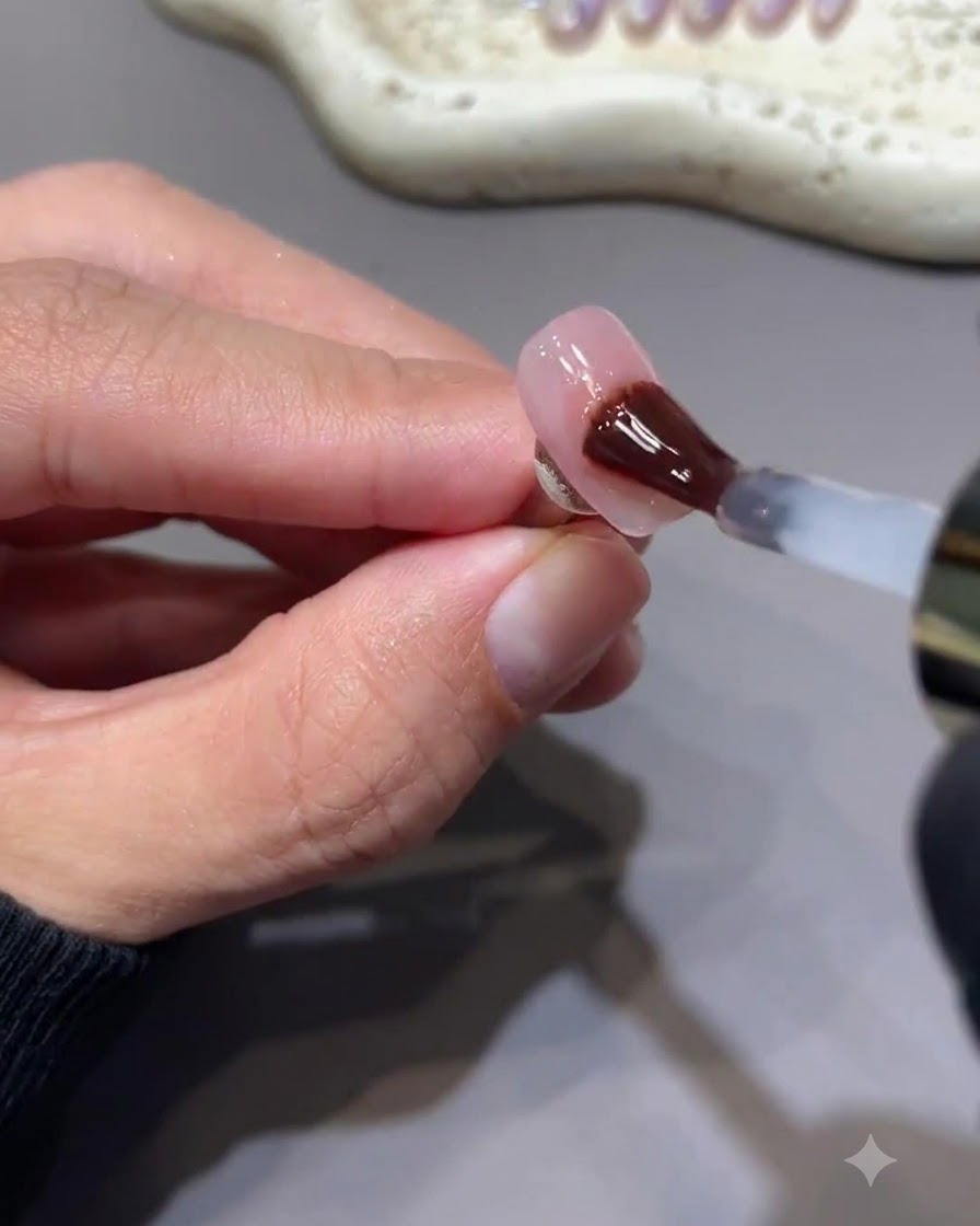 Ein Pinsel trägt einen glänzenden, nicht klebrigen Gel-Top-Coat auf einen Nagel mit berryrosa Stern-Art auf.