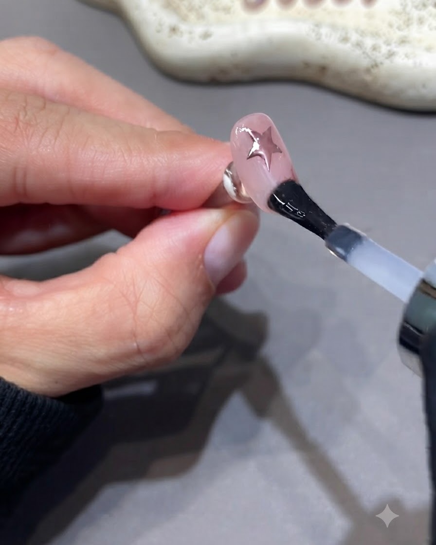 Ein Pinsel trägt eine zusätzliche Schicht Versiegelungs-Top-Coat auf einen manikürten Nagel auf.