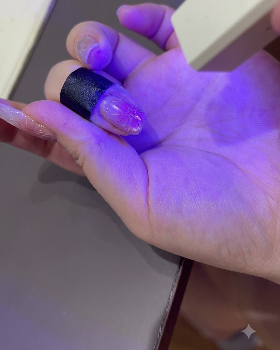 Zadbana dłoń utwardzająca się pod fioletowym światłem przenośnej lampy UV/LED do paznokci.