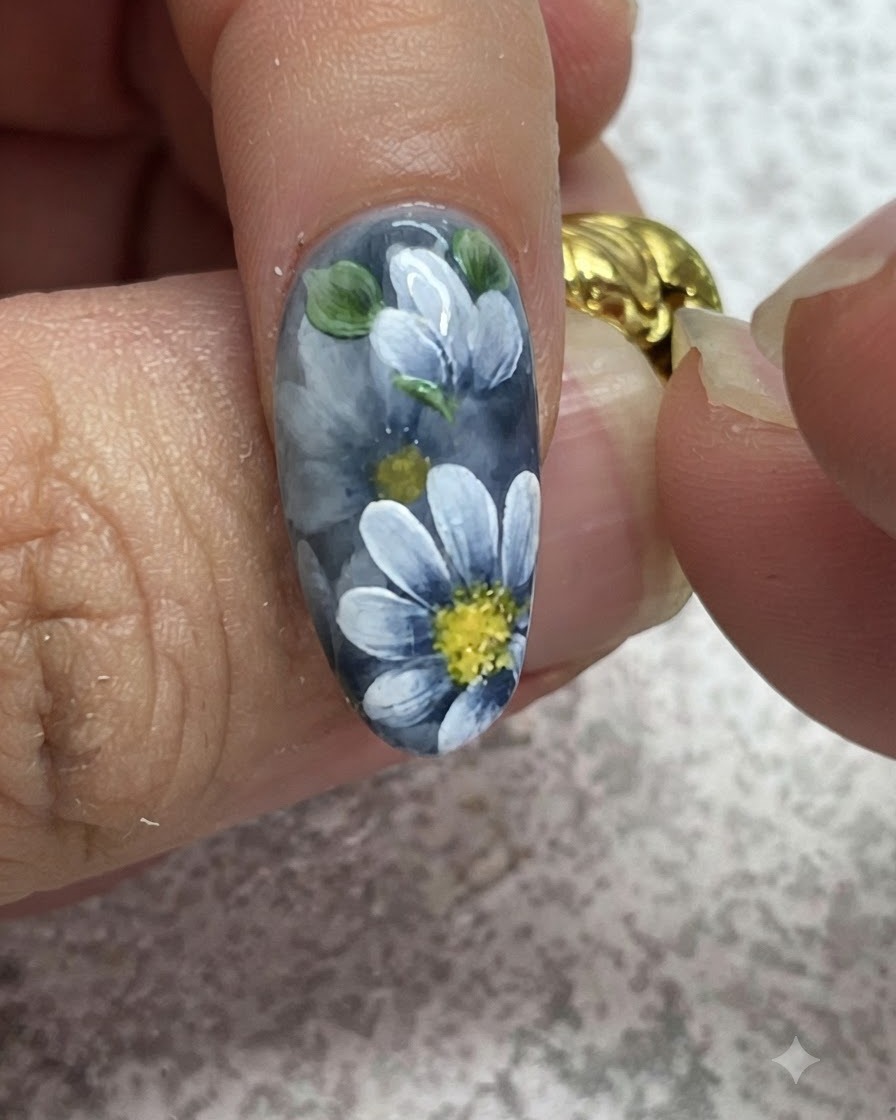 Cienki pędzelek dodający szczegółowe rozświetlenia na namalowanych zielonych liściach przy szarym manicure hybrydowym.