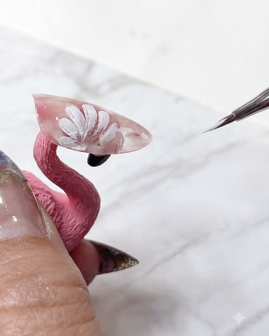 Cienki pędzelek do nail artu poprawiający ostre białe końcówki warstwowych płatków stokrotki na transparentnym różowym przedłużeniu.