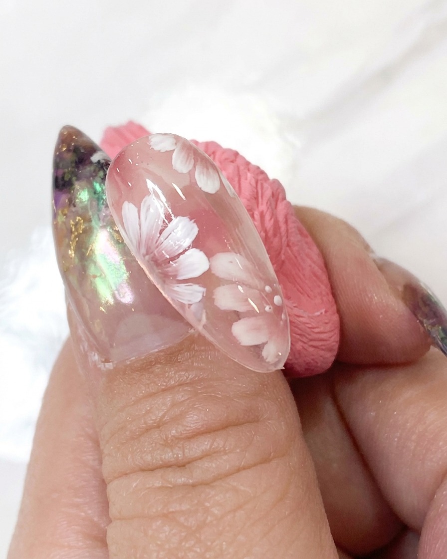 Sonda do zdobień aplikująca malutkie białe kropki akcentujące wokół środka kwiatu w szczegółowym projekcie nail art.