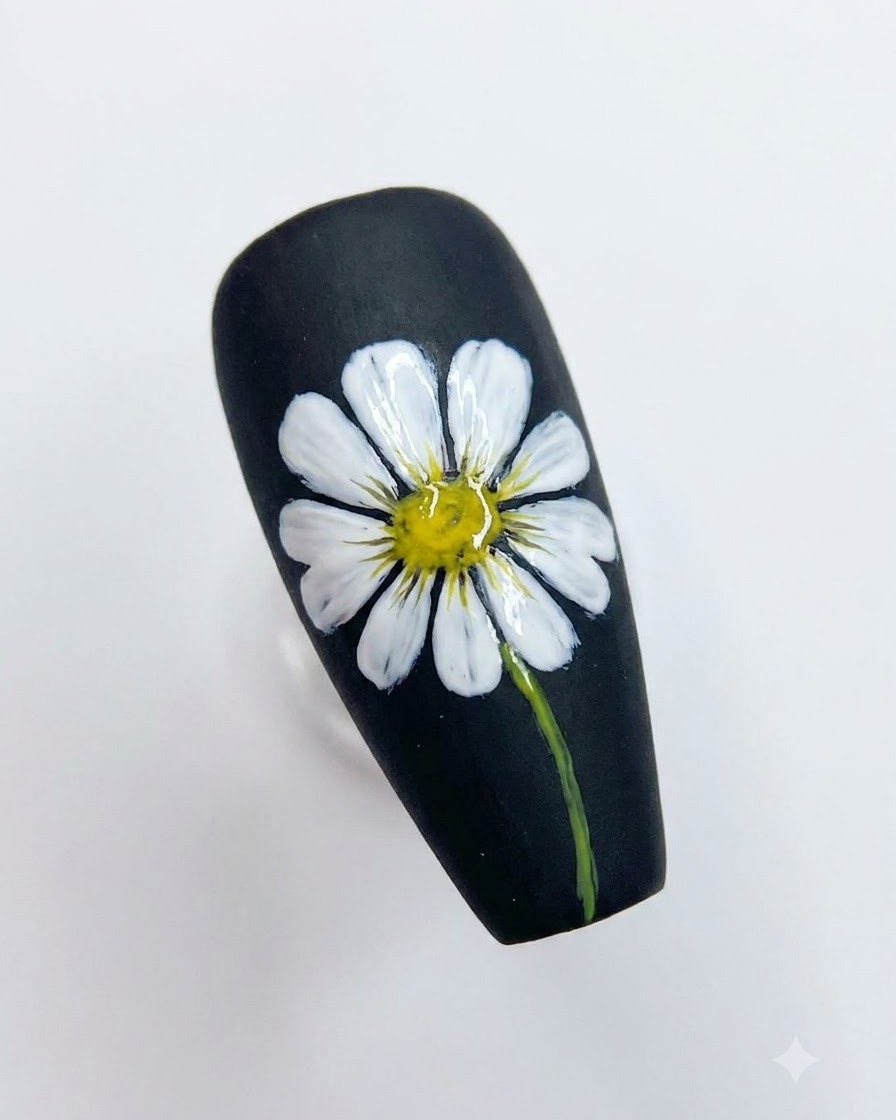 Ukończony czarny projekt nail art z detalami białej stokrotki z jasny żółtym środkiem i zieloną łodygą.