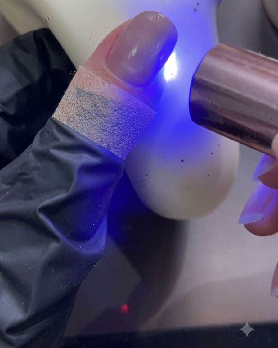 Przenośna lampa UV/LED do paznokci utwardzająca świeżo pomalowany paznokieć w jasnoniebieskim świetle.
