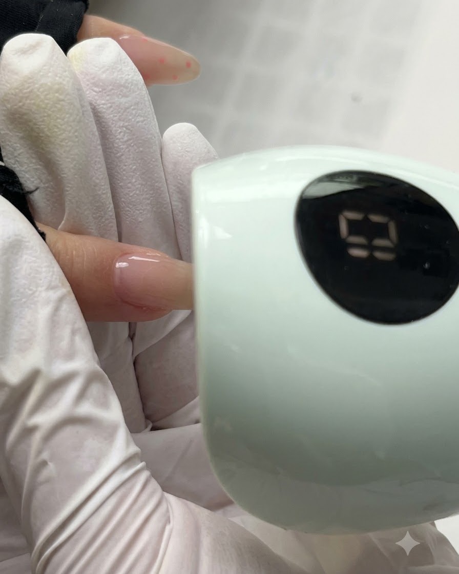 Paznokieć utwardzający się pod kompaktową zieloną lampą UV/LED z widocznym cyfrowym wyświetlaczem czasu.