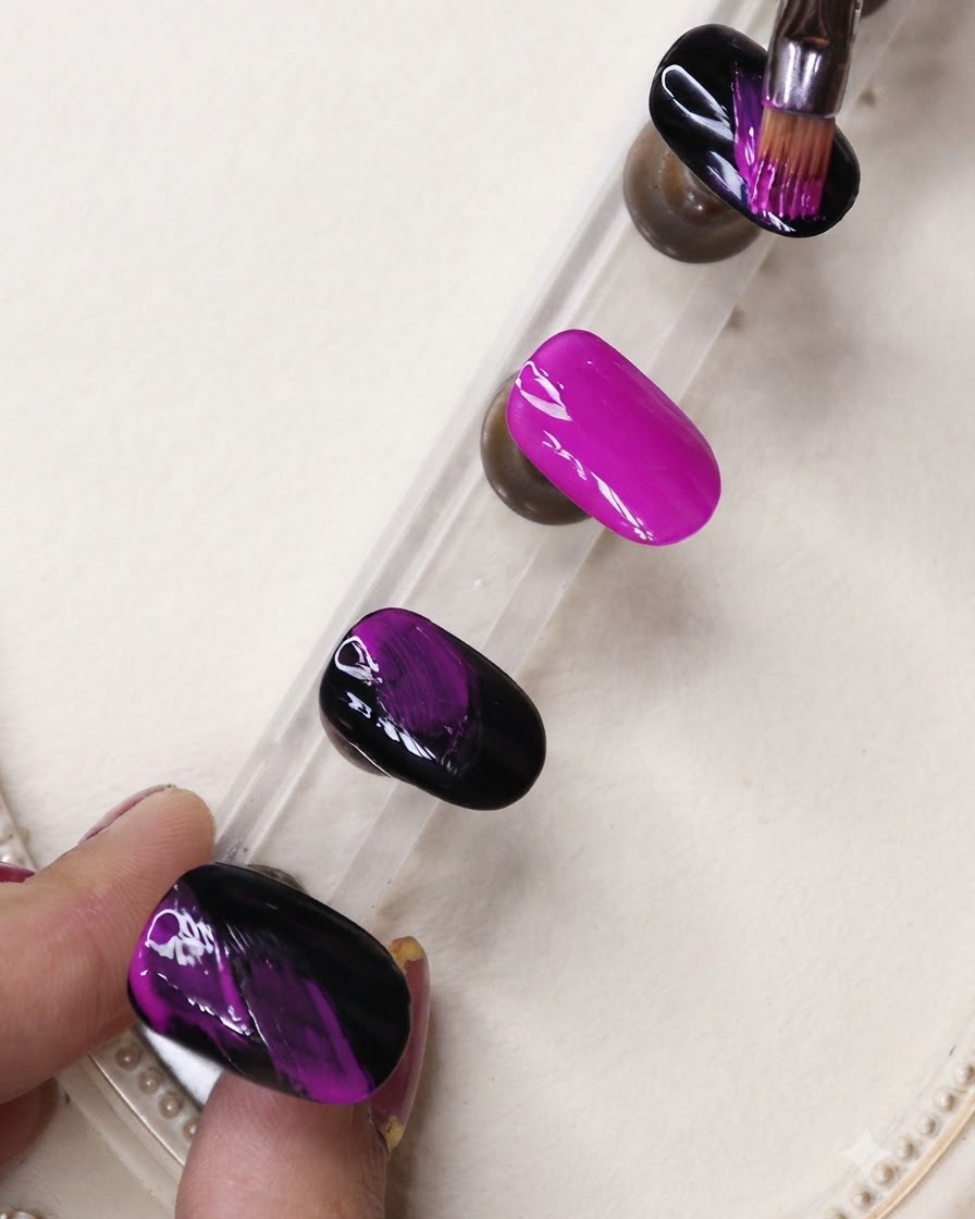 Ein feiner Liner-Pinsel trägt schwarze Gel-Streifen über einen lebendigen Neon-Lila-Nagel auf einem Display-Ständer auf.