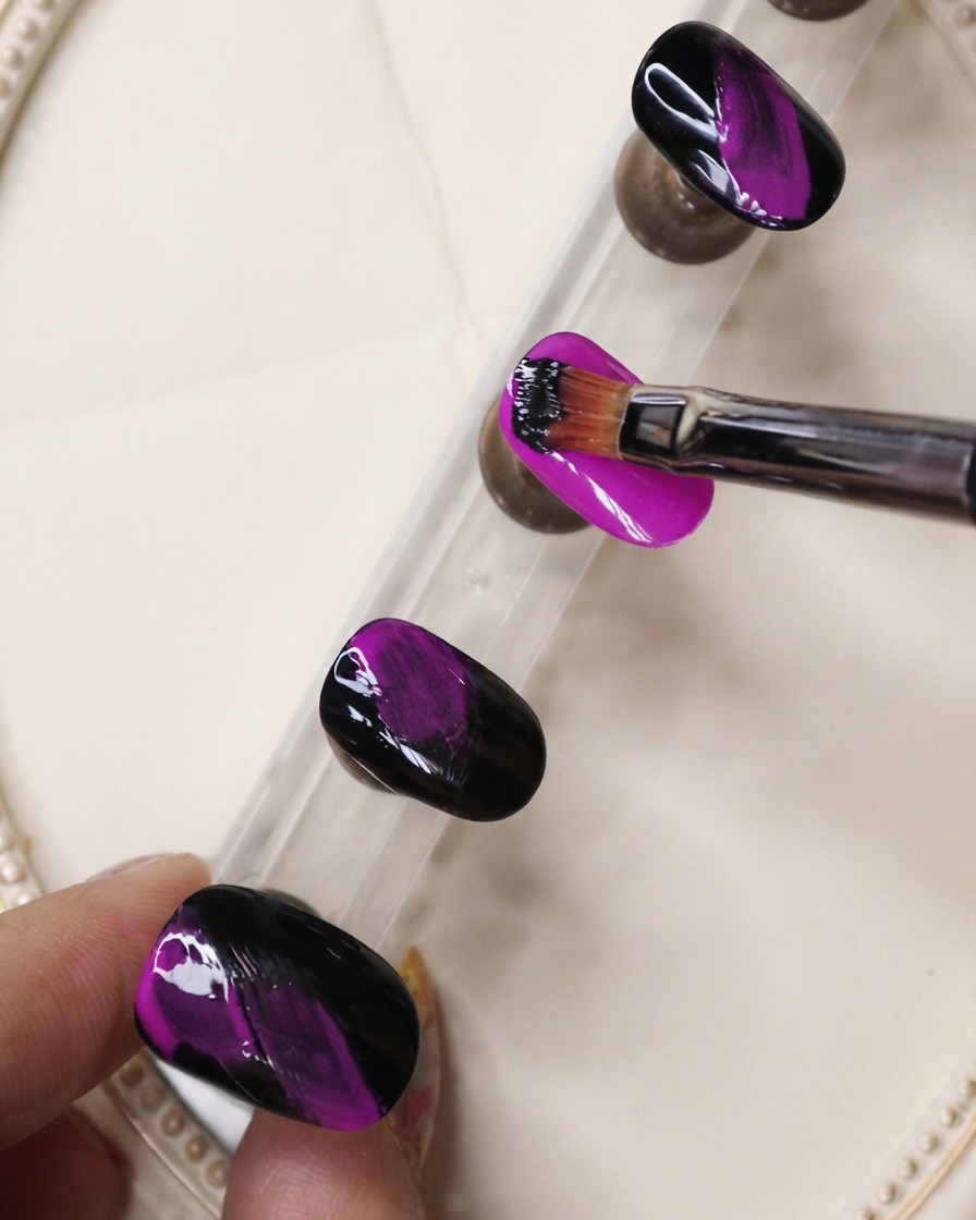 Ein feiner Liner-Pinsel trägt schwarzes Gel in texturierten Strichen über einen Neon-Lila-Nagel auf.