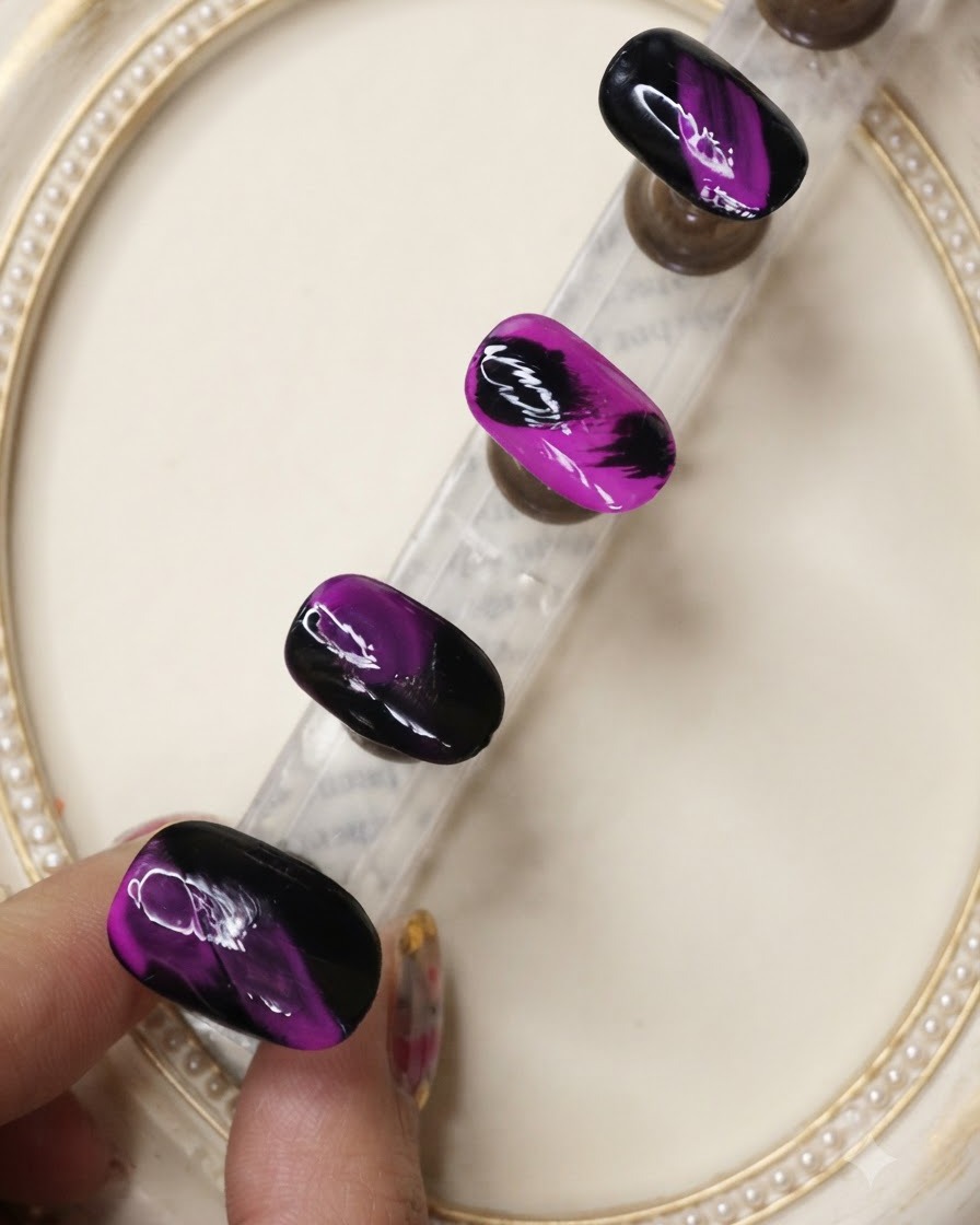 Ein Überlack-Pinsel trägt eine schützende Schicht über die texturierten Nageldesigns in Schwarz und Neon-Lila auf.
