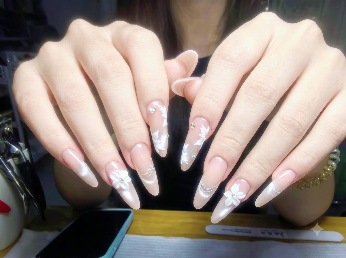 Dłonie spoczywające na stole do manicure z buteleczkami lakierów i profesjonalnymi narzędziami uporządkowanymi w tle.