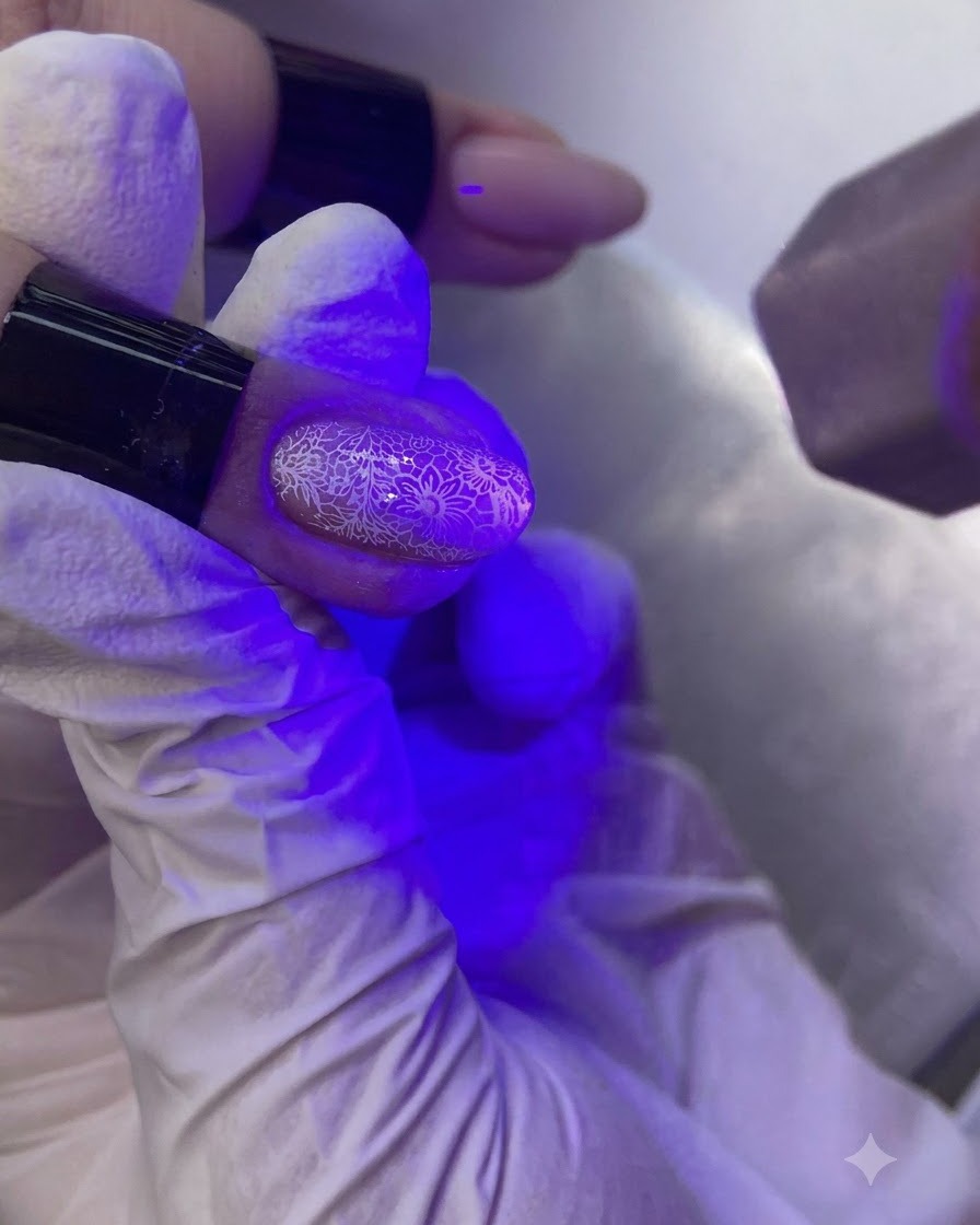Dłoń pod fioletową lampą UV/LED utwardzająca ozdobiony paznokieć.
