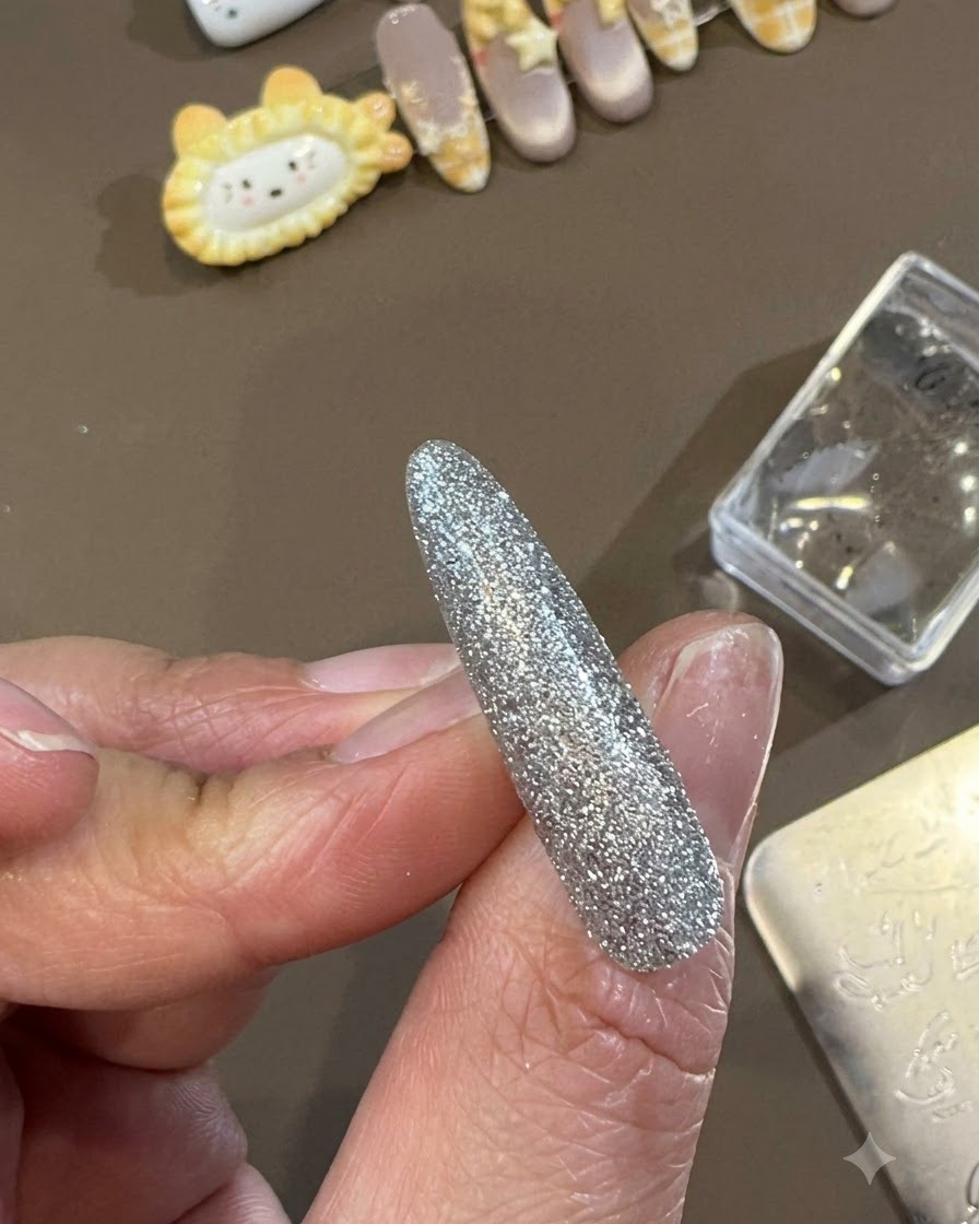 Pędzelek z żelem top coat rozprowadzający gładką, błyszczącą warstwę wierzchnią na ukończonym, dekoracyjnym wzorze paznokcia.