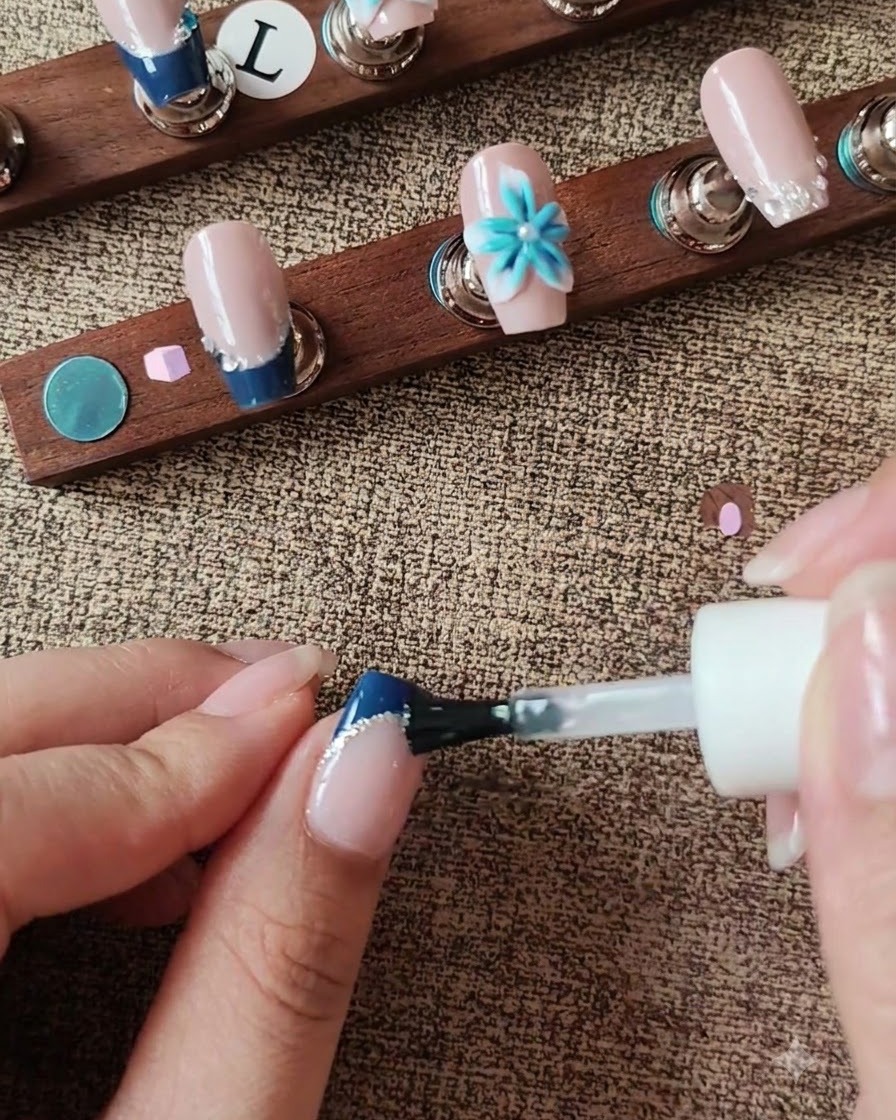 Pędzelek aplikujący top coat na powierzchnię paznokcia omijając akcent florystyczny 3D.