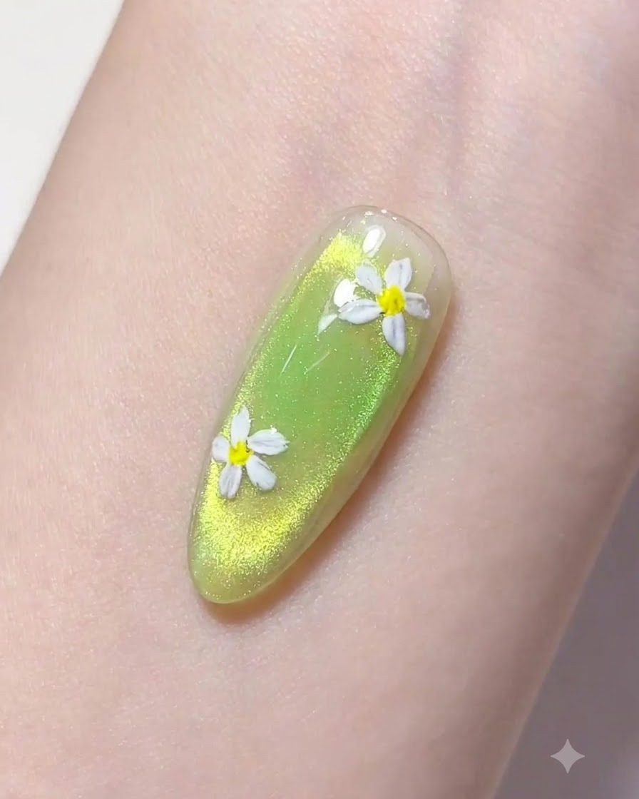 Cienki pędzelek liner nabierający kroplę przezroczystego żelu budującego nad zielonym manicure.