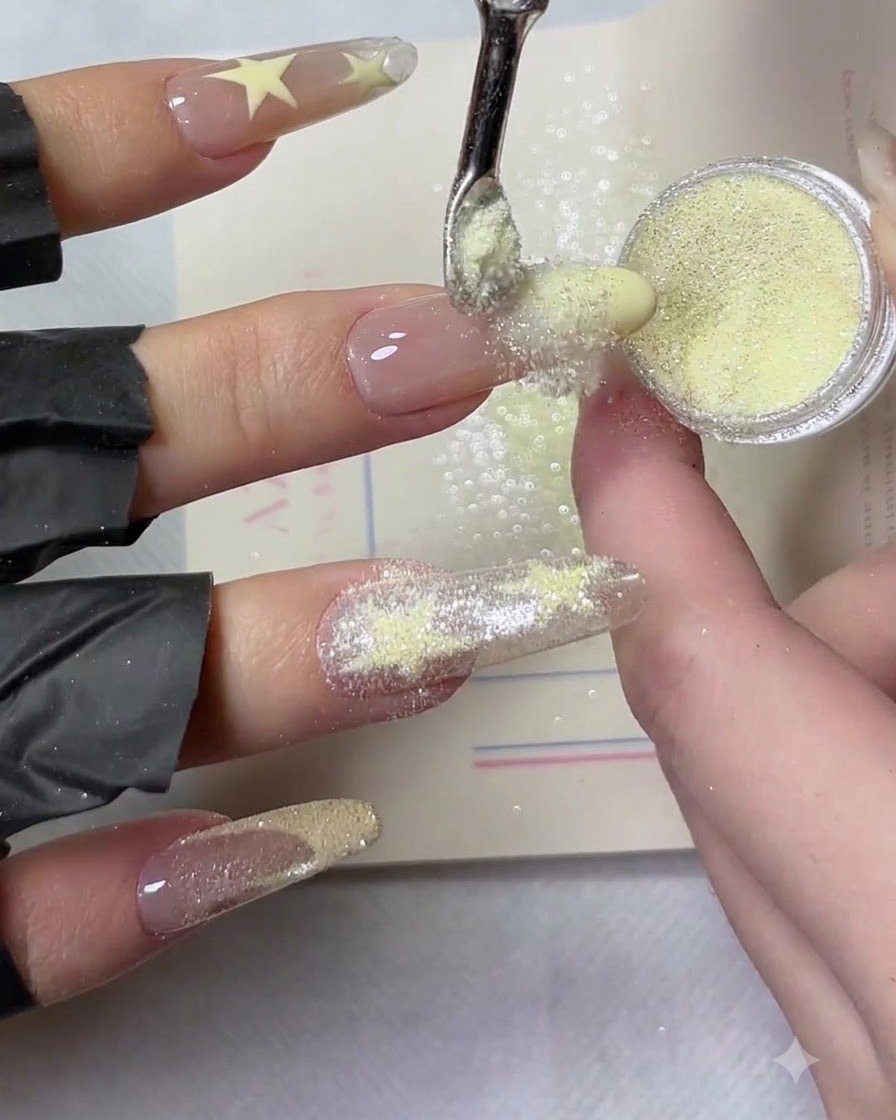 Zbliżenie żółtego pyłka crushed diamond rozsypywanego równomiernie po mokrej, żółtej końcówce manicure french.
