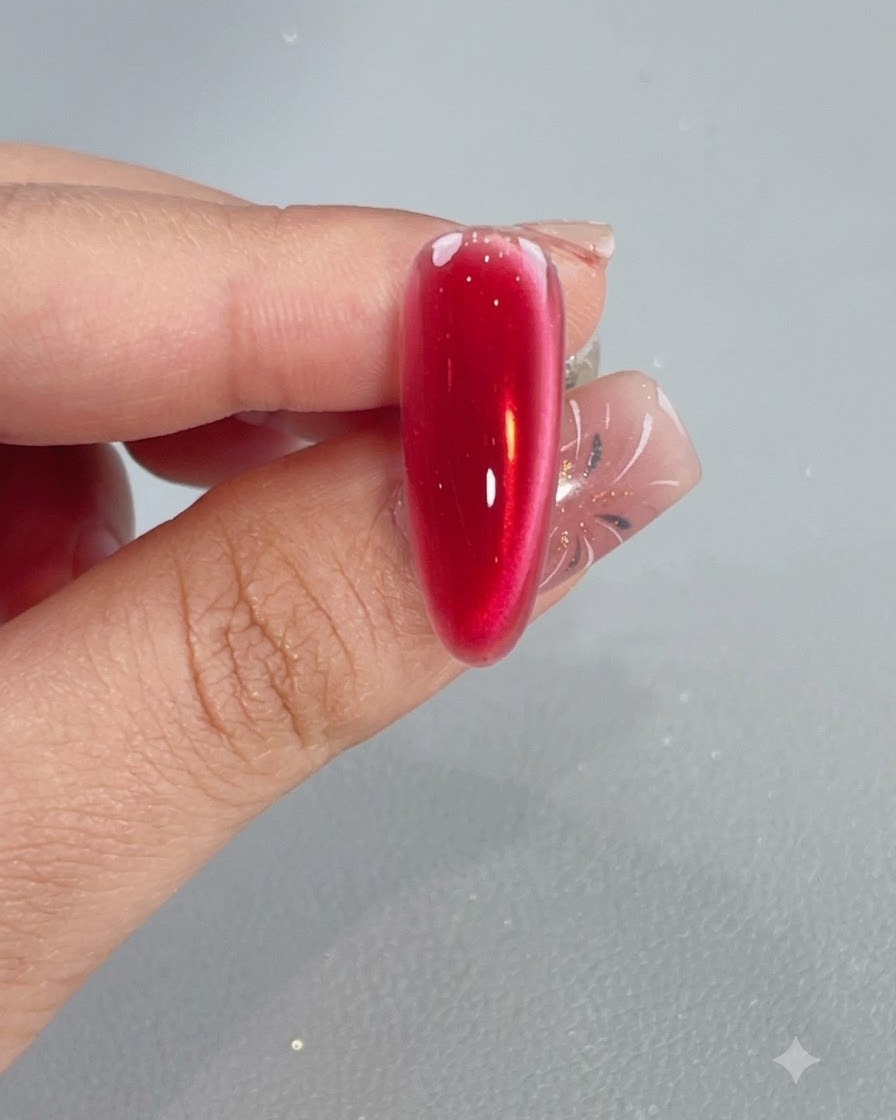 Pędzelek aplikujący błyszczącą warstwę top coat na utwardzony, krystaliczny czerwony paznokieć cat eye.